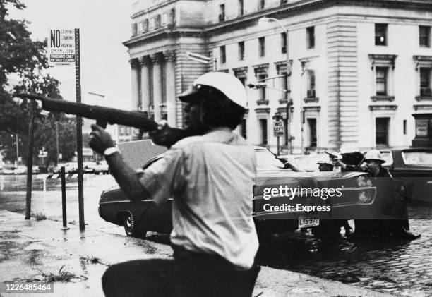 Newark police officers and state troopers exchange fire with a sniper during the race riots in Newark, New Jersey, 16th July 1967. The riots were...