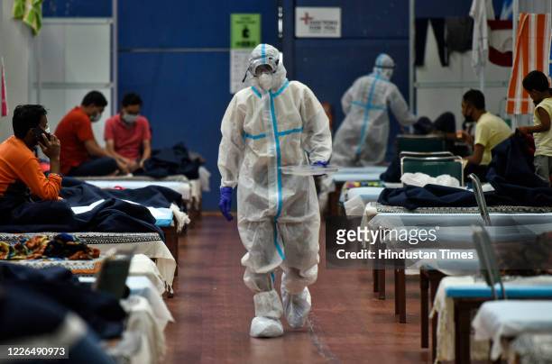Health worker in PPE coveralls while serving food to Covid-19 patients housed at the Commonwealth Games Village Sports Complex which is a temporary...