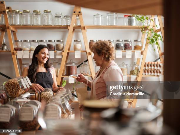 gelukkige spaanse werknemer en klant die bij elkaar glimlachen - food market stockfoto's en -beelden