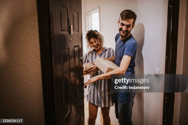 happy young couple receiving packets from postal worker - looking through hole stock pictures, royalty-free photos & images