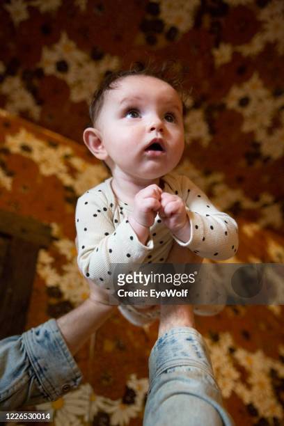 low angle pov shot of a father holding his baby up over his head. - baby pov stock-fotos und bilder