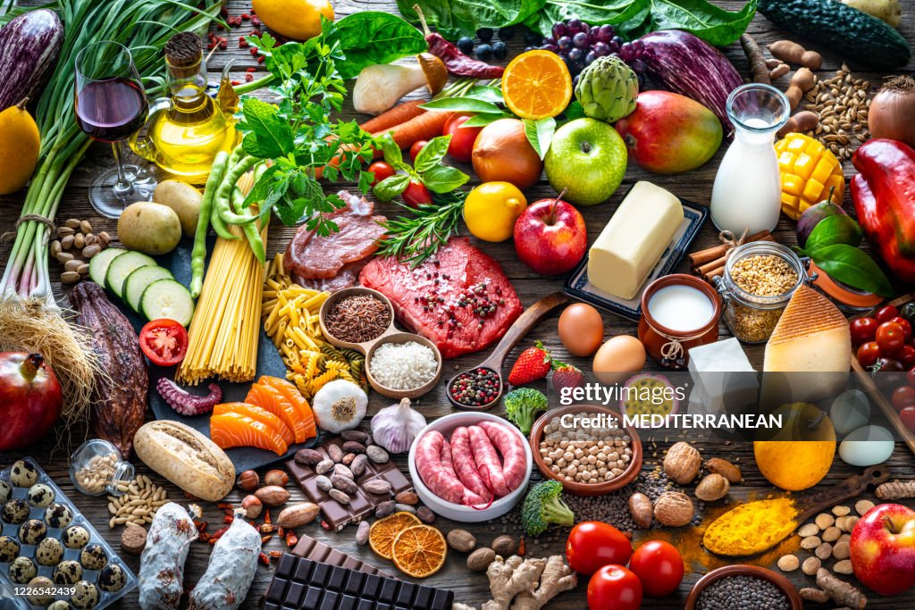 Varied food carbohydrates protein vegetables fruits dairy legumes on wood