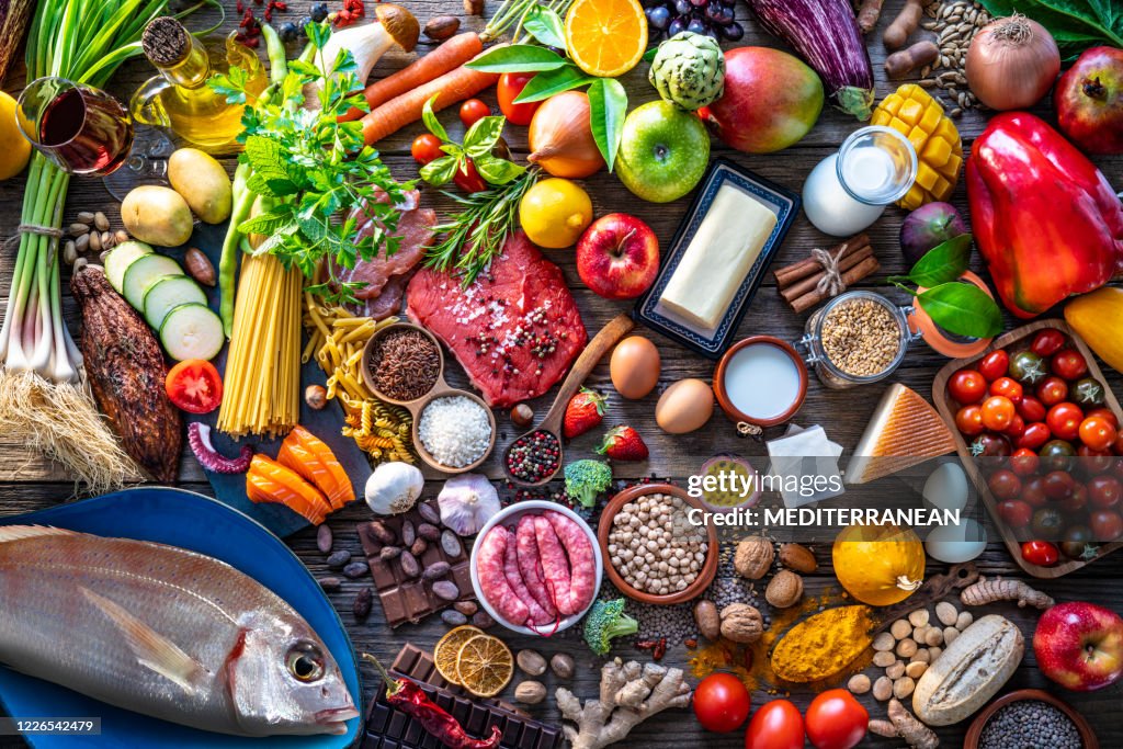 Varied food carbohydrates protein vegetables fruits dairy legumes on wood