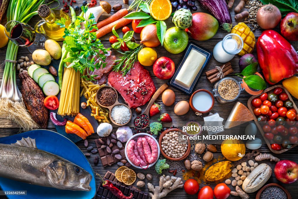 Varied food carbohydrates protein vegetables fruits dairy legumes on wood
