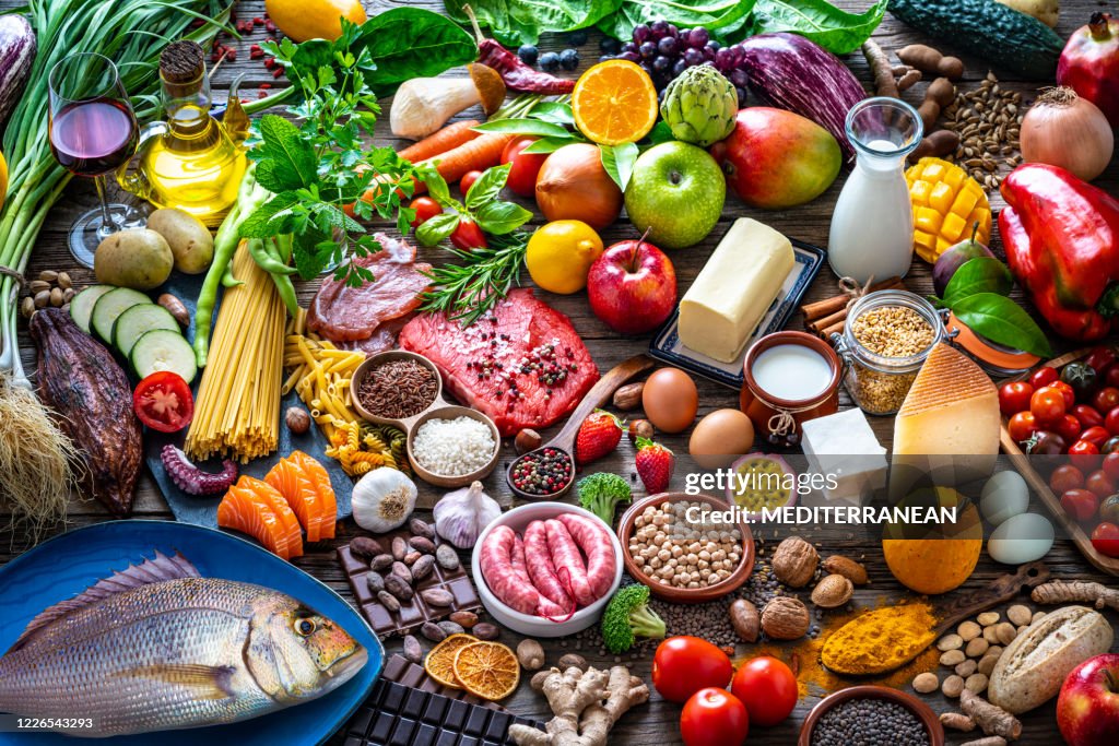 Varied food carbohydrates protein vegetables fruits dairy legumes on wood