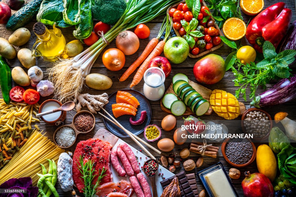 Varied food carbohydrates protein vegetables fruits dairy legumes on wood