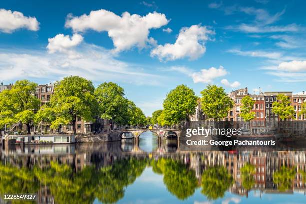 reflection of bridge in amsterdam on a summer day - amsterdam canals stockfoto's en -beelden
