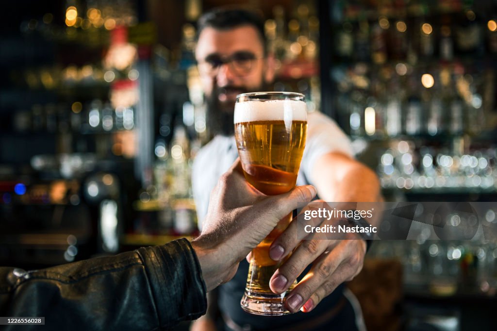 Bartender offering a beer in pub