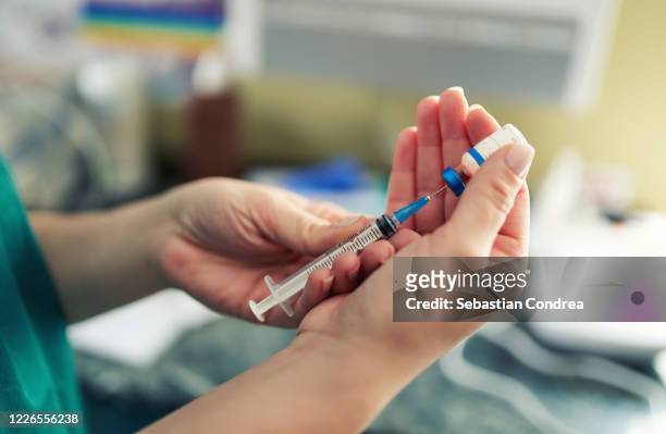 doctor preparing the coronavirus covid-19 vaccine. details of hands and syringe. - syringe stock pictures, royalty-free photos & images