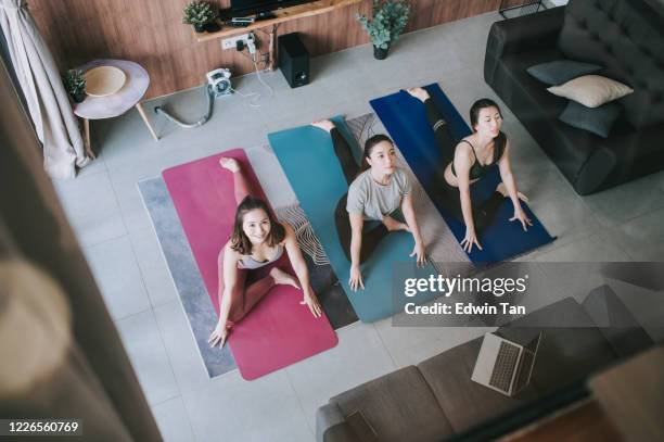 a group of asian chinese female friends practicing yoga in domestic living room together using laptop for online class - working on laptop in train top view stock pictures, royalty-free photos & images