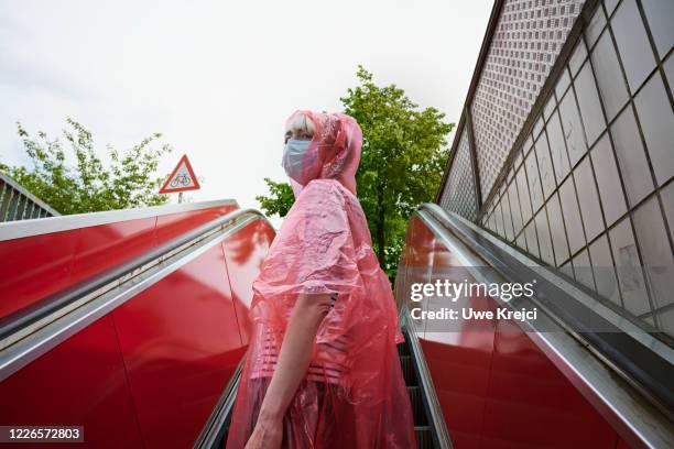 woman going up on escalator - raincoat ストックフォトと画像
