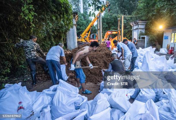 This photo taken on July 11, 2020 shows workers preparing anti-flood measures at a gate of a park along the Yangtze River in Wuhan in China's central...