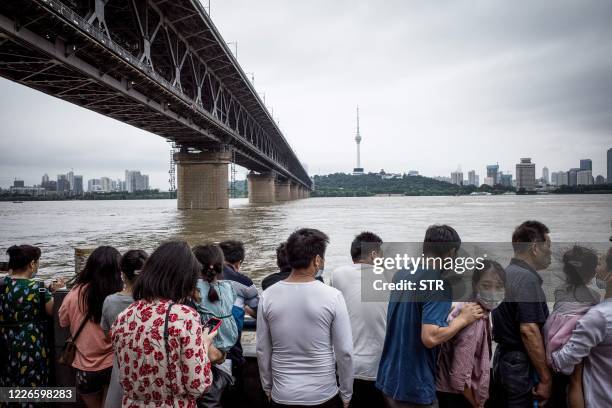 This photo taken on July 12, 2020 shows residents looking at the swollen Yangtze River in Wuhan in China's central Hubei province. - Various parts of...