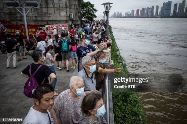 This photo taken on July 12, 2020 shows residents looking at the swollen Yangtze River in Wuhan in China's central Hubei province. - Various parts of...