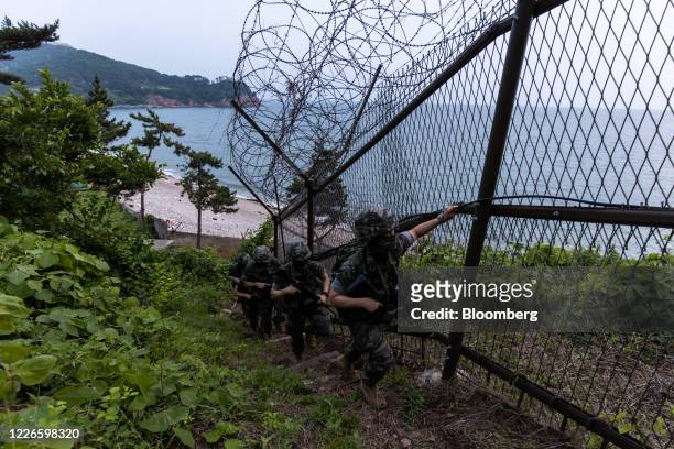 South Korean Marine Corps soldiers walk past a razor-wire fence while patrolling on Yeonpyeong Island, South Korea, on Friday, June 26, 2020. On the...