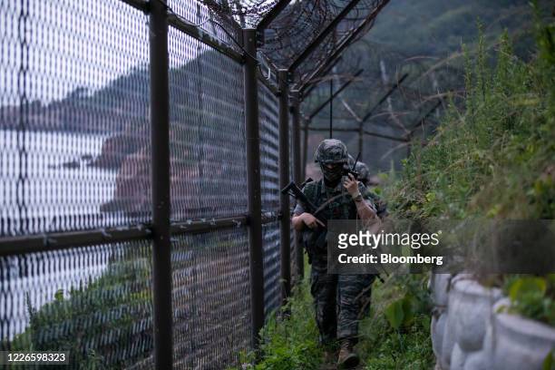 South Korean Marine Corps soldiers walk past a razor-wire fence while patrolling on Yeonpyeong Island, South Korea, on Friday, June 26, 2020. On the...