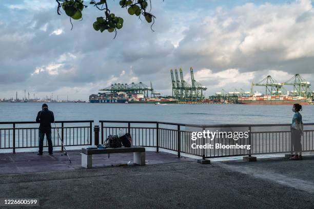 Man goes fishing off Labrador Nature Reserve as container ships are docked at Pasir Panjang Terminal in Singapore, on Monday, July 13, 2020. Prime...