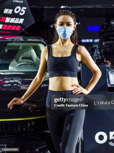 Masked model poses by a car at an auto show in Nanning in south China's Guangxi Zhuang Autonomous Region Saturday, July 11, 2020.- PHOTOGRAPH BY...