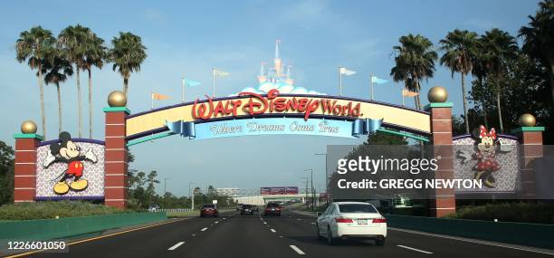 Visitors drive past a sign welcoming them to Walt Disney World on the first day of reopening of the iconic Magic Kingdom theme park in Orlando,...
