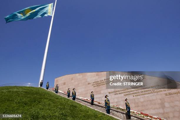 Kazakh honour guards wearing face masks stand at attention by the national flag flying at half-mast on the national day of mourning for people who...