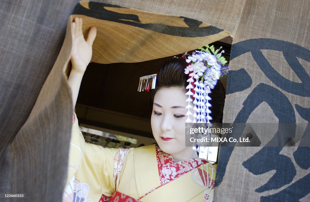 A geisha woman coming out from a shop