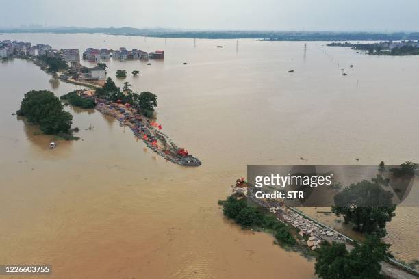 This aerial view shows workers repairing a breached dam due to flooding in Jiujiang in China's central Jiangxi province on July 13, 2020. - Floods...