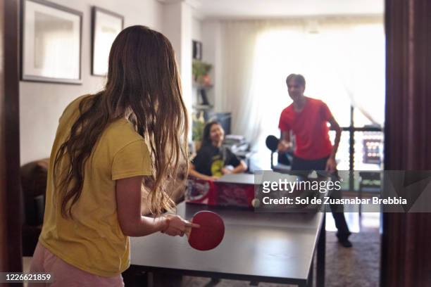 family entertaining themselves doing sports playing ping-pong in their living room - friends table tennis stock pictures, royalty-free photos & images