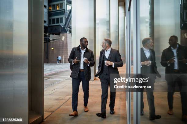 male business colleagues walking and talking with coffee - no tie stock pictures, royalty-free photos & images