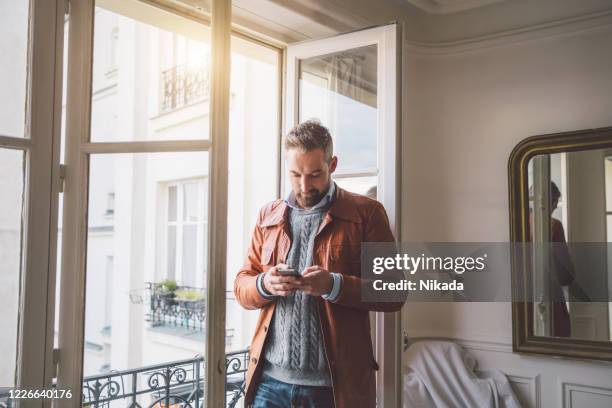 bebaarde mens die op smartphone leest - paris stock exchange stockfoto's en -beelden