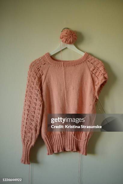 knitted sweater in peach color with one sleeve finished, another in progress - unvollständig stock-fotos und bilder