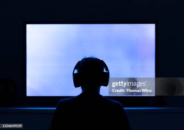 person with head phones looking at tv screen - game one stockfoto's en -beelden