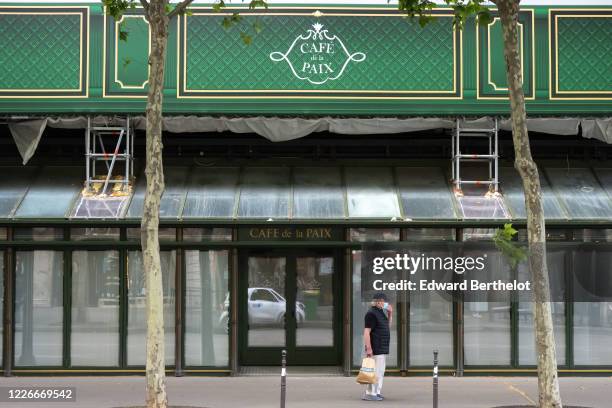 Passerby wearing a face mask, walks in front of the closed Cafe de la Paix as the lockout continues due to the epidemic of coronavirus on May 23,...
