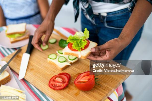 jonge vrouw die een sandwich maakt. - een broodje smeren stockfoto's en -beelden