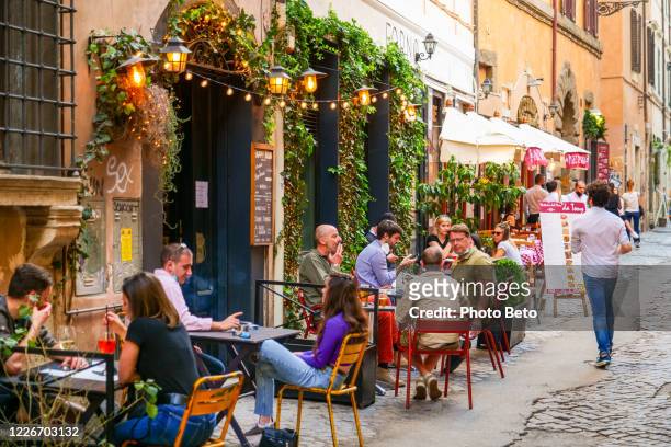 alcuni clienti si godono un aperitivo in un bar nell'antico quartiere trastevere a roma - cultura italiana foto e immagini stock