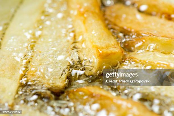 extreme closeup of french fries frying in oil - gefrituurd stockfoto's en -beelden