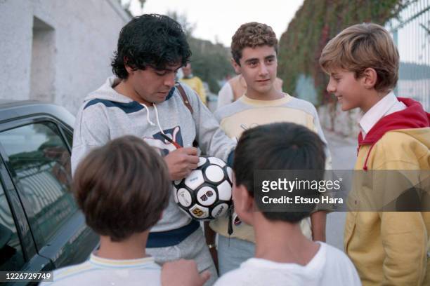 Diego Maradona of Napoli sign autographs for fans after a training session at the Centro Paradiso di Soccavo on October 17, 1986 in Naples, Italy.