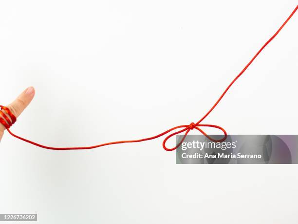 a red thread legend. a person's hand with a red thread tied on its little finger - koord stockfoto's en -beelden