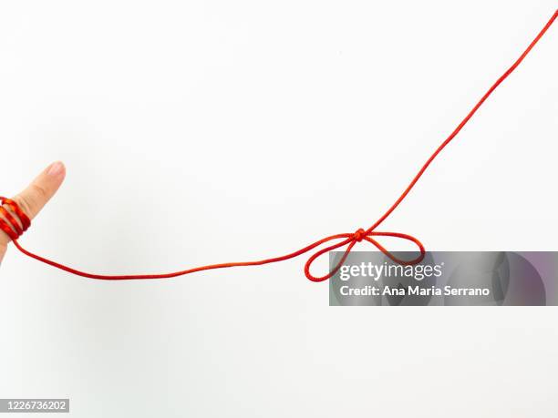 a red thread legend. a person's hand with a red thread tied on its little finger - tie ribbon bow stock pictures, royalty-free photos & images