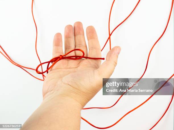 a red thread legend. a person's hand with a red thread tied on its little finger - mani fili foto e immagini stock