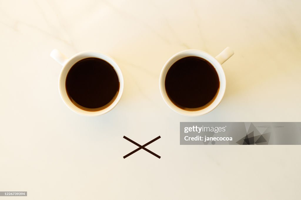 Two cups of coffees arranged as human face with line showing emotion. dissatisfied