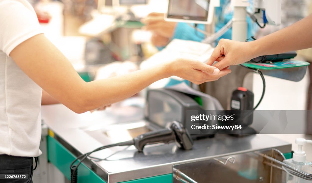 Female hand with coin money pay for goods concept. Hand giving cash and hand receiving cash, paying checkout at cashier access in supermarket.