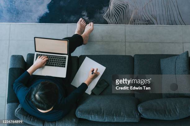 an asian chinese mid adult having breakfast in dining room while using laptop to reply emails in the morning - telecommuting stock pictures, royalty-free photos & images