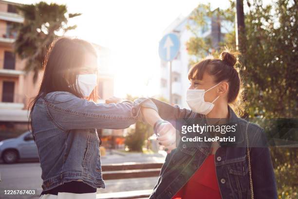 vrienden eindelijk weer ontmoeten in de straten, bedrijf hand het dragen van beschermende handschoenen - elbow stockfoto's en -beelden