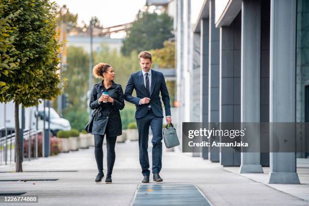corporate partners walking and talking on way to work - man talking to camera stock pictures, royalty-free photos & images