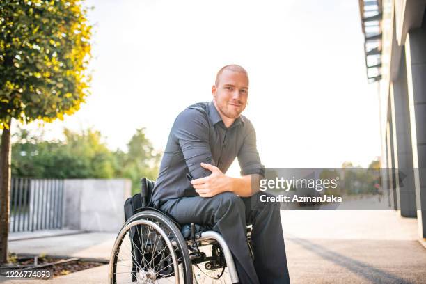 outdoor portrait of relaxed young businessman in wheelchair - wheelchair stock pictures, royalty-free photos & images