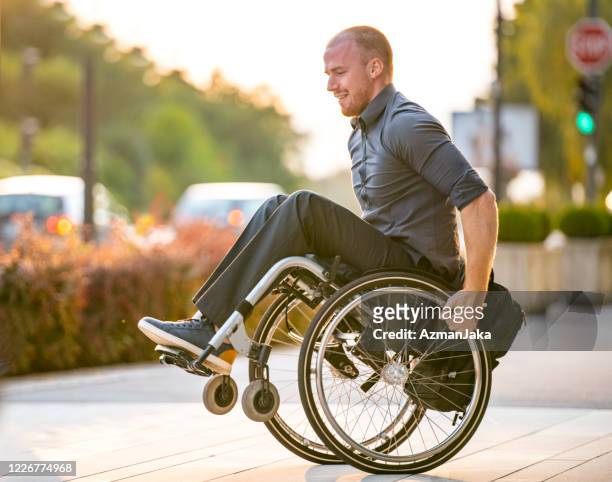 zakenman met fysieke onbekwaamheid die stunts met rolstoel doet - wheelie stockfoto's en -beelden