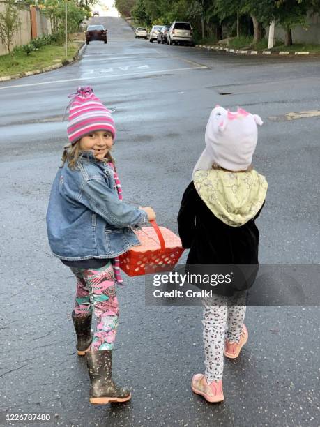 two little child friends, walking down the street after the rain, on a cold day. - brazil rain boots stock pictures, royalty-free photos & images