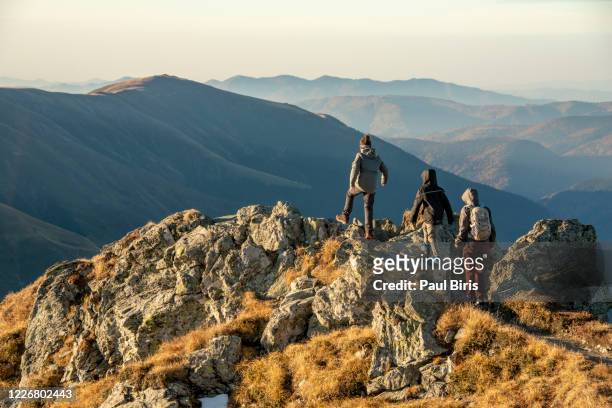 mother with her sons descending from buteanu peak in fagaras mountains, romania - escursionismo foto e immagini stock