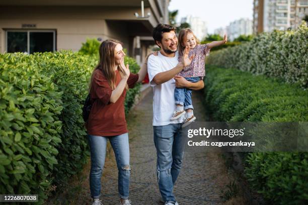 happy family walking in front of their house - family waving stock pictures, royalty-free photos & images