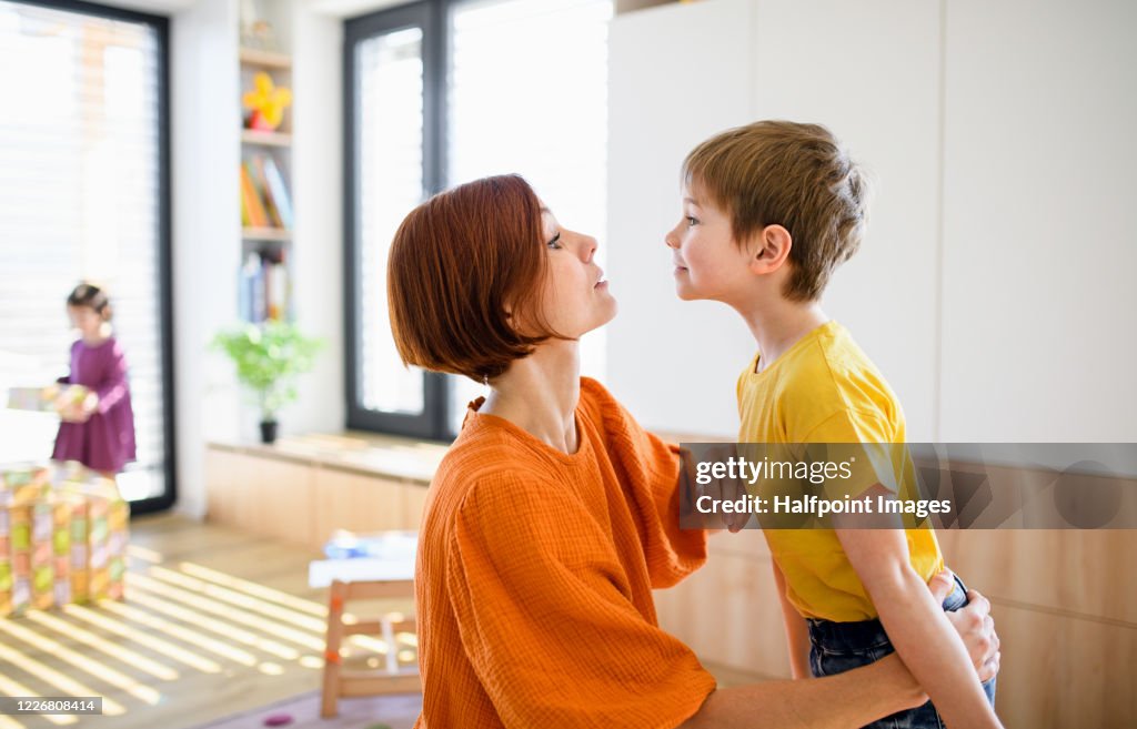 Mother with small son indoors in the morning at home, getting dressed.